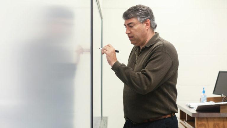 Faculty member writing something on board